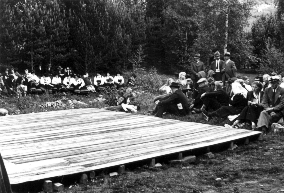 Anna Grostøl, Valle Setesdal, Aust-Agder 1939. Bondestevne. Forberedelse til dansing av gangar. Tilskuere og dansere sitter rundt scenen.