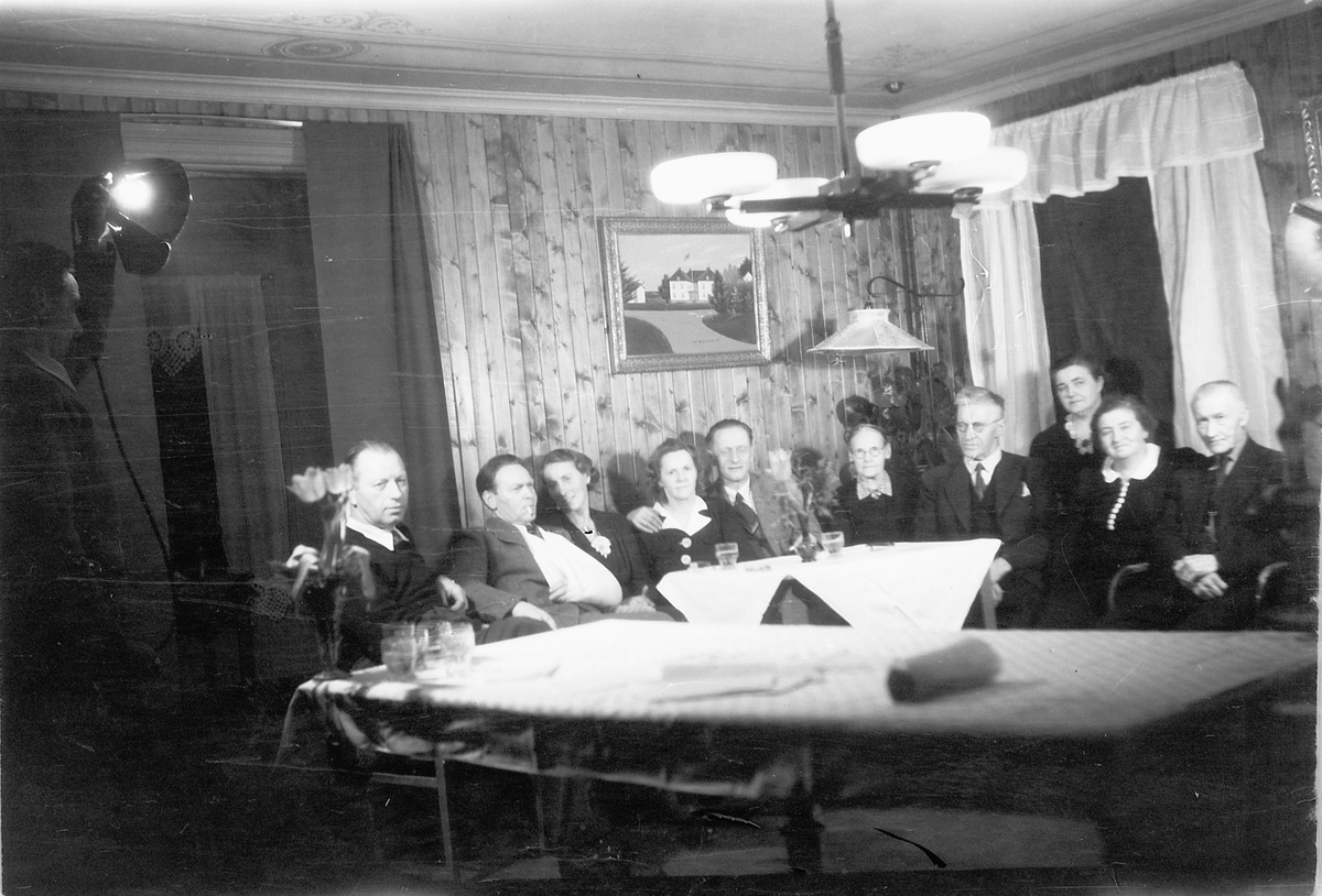 Håkon Prestkværn, Interiør, stue. Mann nr. 2 (med fatle) er Kolbjørn Prestkværn. Deretter hans kone Gunhild, Martha (f. Prestkværn) og Paul Pettersen, og Gunda Prestkværn.