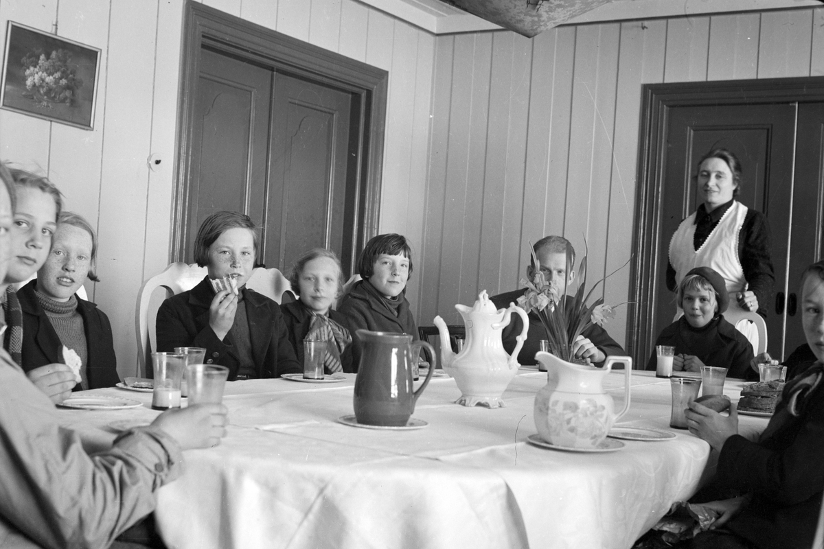 Håkon Prestkværn, Gruppe ukjente rundt bord, frokost, måltid, barn og voksne. Ukjent sted.