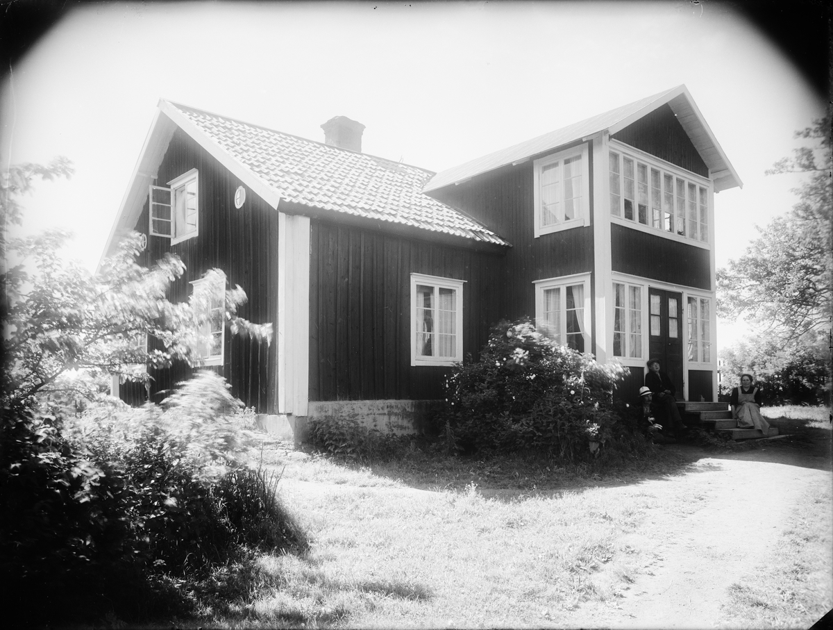 Skötsner-Edhlund, Man, kvinna och barn sitter på trappan, Raggarön, Börstils socken, Uppland