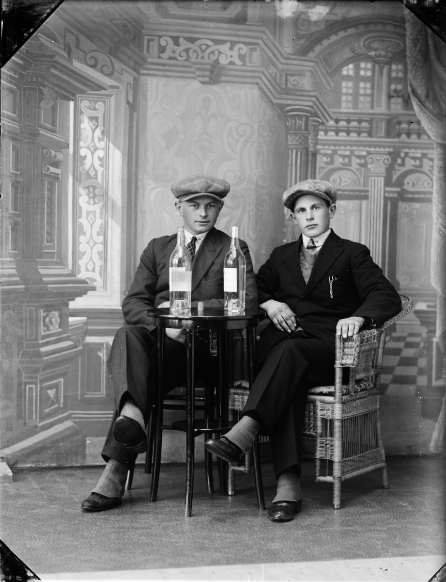 Skötsner-Edhlund, Ateljéporträtt - två unga män sitter vid ett bord med flaskor på, Östhammar, Uppland 1929