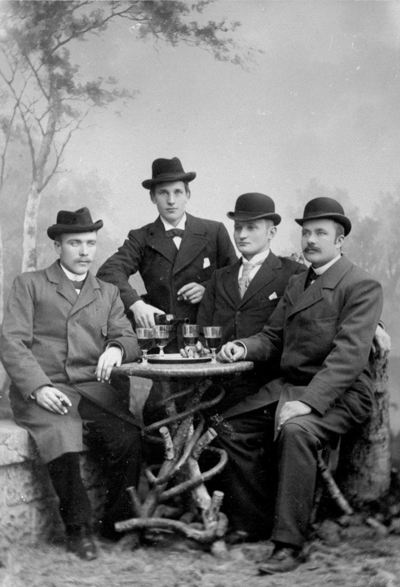 Anno Domkirkeodden, 4 menn i fotostudio. vinglass på bordet, til høyre er Otto Frydenlund, Brumunddal.