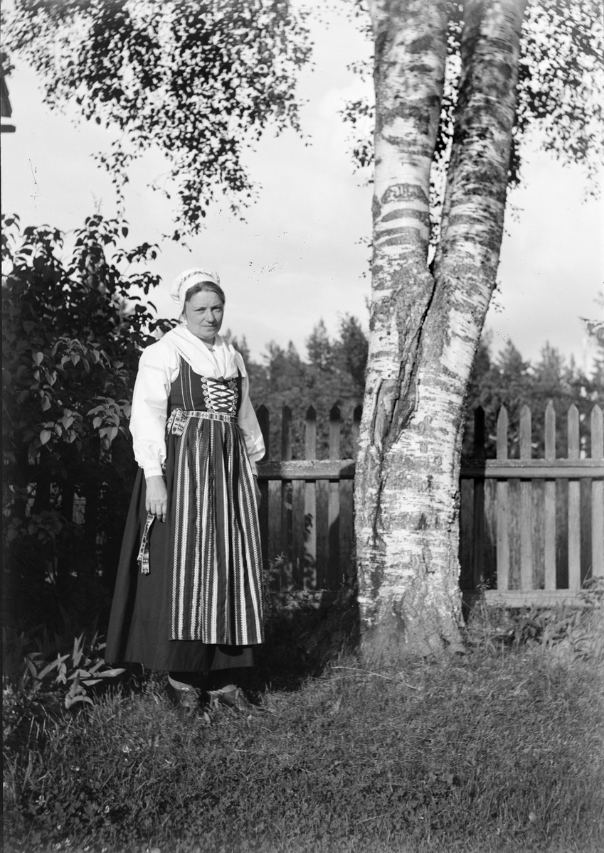 Okänd,, Christiane Liljefors, a dressed folk costume, probably Leksandö, stands by birches, Dalarna
