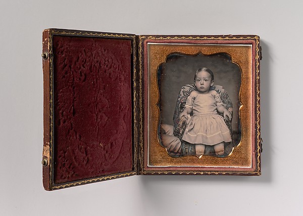Unknown, [Child Sitting on Chair Draped with Floral Print Fabric]