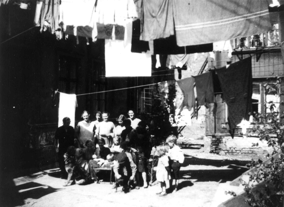 Nanna Broch, Fra gårdsrom, Oslo. Kvinner og barn poserer i gården under klesvask. Fra boliginspektør Nanna Brochs boligundersøkelser i Oslo 1920-årene.