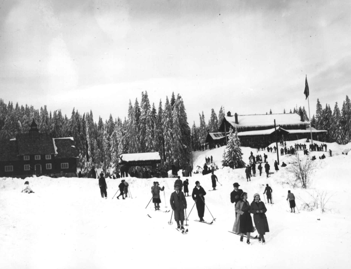 Hermann Christian Neupert, Frognerseteren Restaurant, Nordmarka, Oslo. Vintermotiv. Mennesker på ski. Flaggstang med flagg.