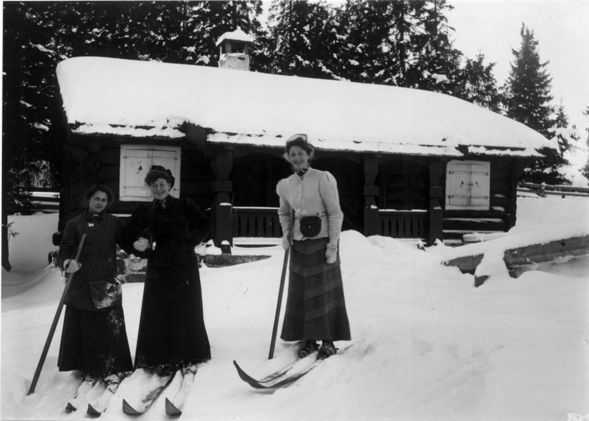 Hermann Christian Neupert, Frognerseteren, Oslo. 1908-1910. Vintermotiv. Kvinnelige skiløpere. En av dem heter frk. Tønder. Hytte i bakgrunnen.