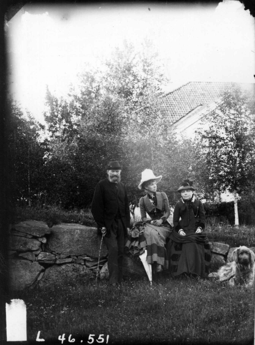 Fredrik Emil Faye, Gruppeportrett, byggmester Nestor Malthe (Haslengård, Eidsvoll), fru Sigrid Malthe, (foreldre til dr. Alexander Malthe), ca. 1887. Sittende i hagen med hatter og hund. Fra portrettserie av personer som bodde på eller besøkte Dal gård, Ullensaker, fotografert av gårdens eier, kammerherre Fredrik Emi…