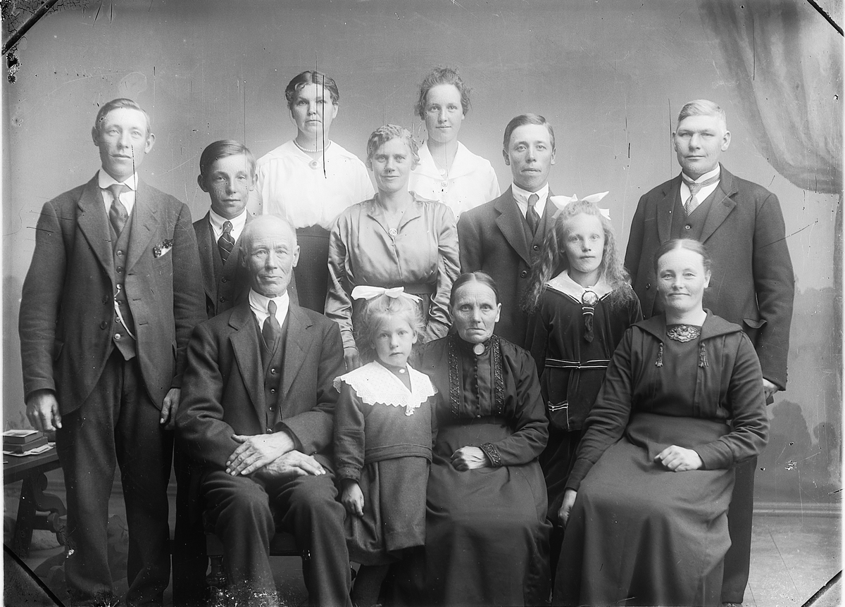 Martin Finborud, Andreas Olsen sin familie. Gardskar på Nedre Hulleberg, Nes Hedmark. Sittende foran er fra venstre far Ole Andreas Olsen (1859-1933), pleiedatter Ester, mor Marie Johansen (1861-1942), stående er Tina f.1909, Anne f.1885. Stående i midten er Johan f.1890, Ottar (1904-1979), Helga (gift med Oddvar),…