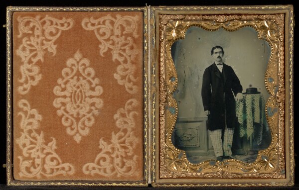 Unknown, [Portrait of Man Standing in Studio with Hat on Table]