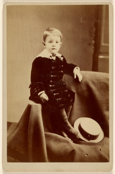 Unknown, [Little boy, seated on cloth, straw hat at feet]