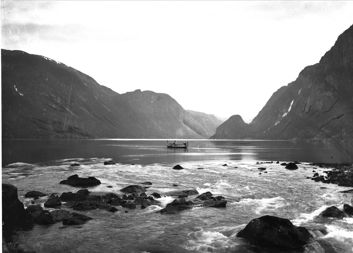 Solveig Lund, Landskapsfotografi fra Odda i Hardanger.Antakelig Sørfjorden med fiskeskute. I forgrunnen elveutløp.