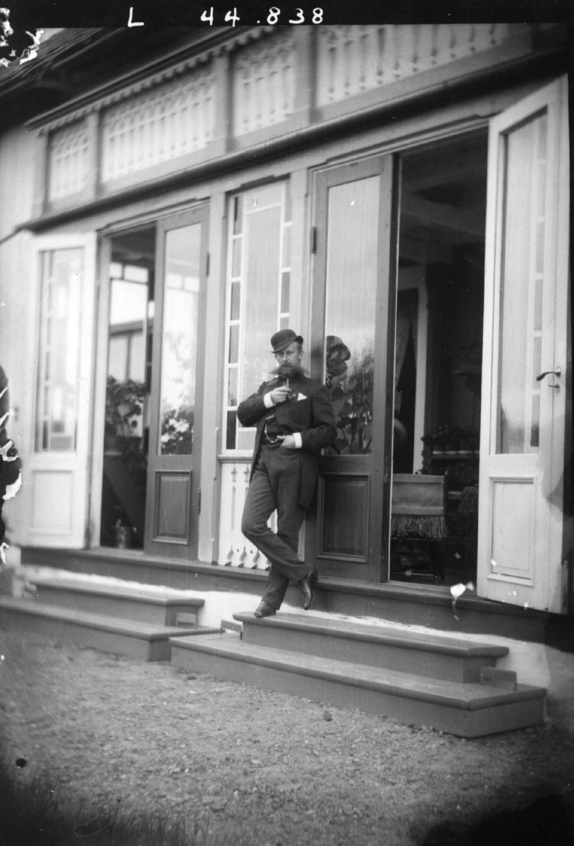 Fredrik Emil Faye, Portrett, hoffstallmester G. Sverdrup poserer foran inngangsparti. Fra portrettserie av personer som bodde på eller besøkte Dal gård, Ullensaker, fotografert av gårdens eier, kammerherre Fredrik Emil Faye (1844-1903) i årene 1875-1900.