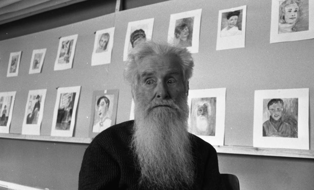Örebro Kuriren, Ryss målar 18 april 1966 En rysk man med långt silvervitt hår och skägg. I bakgrunden syns en vägg fylld med målningar som han har gjort. Han är klädd i mörk tröja. or. Han går nedför en kort trappa utomhus.