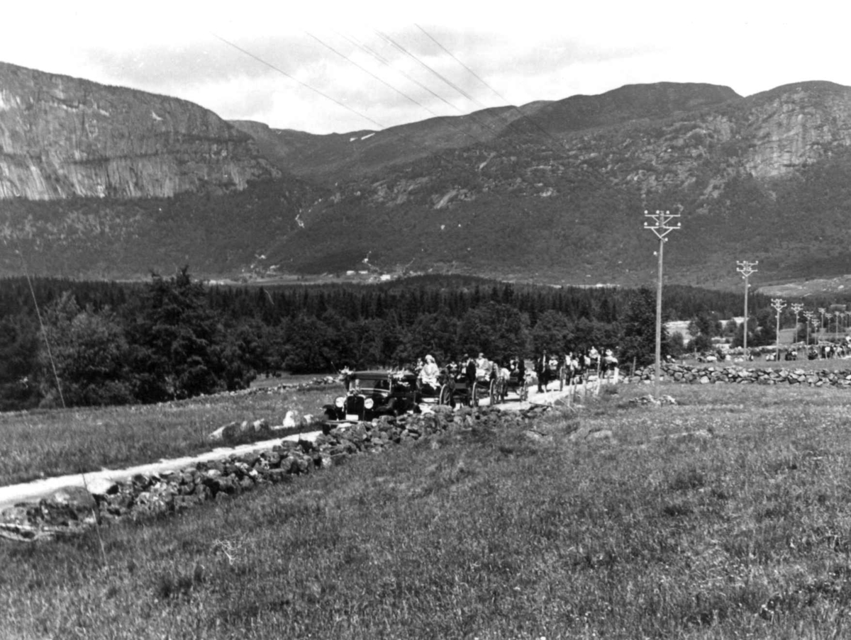 Anna Grostøl, Valle, 1939. Bryllupsfølge med bil, hest og vogner på veien.