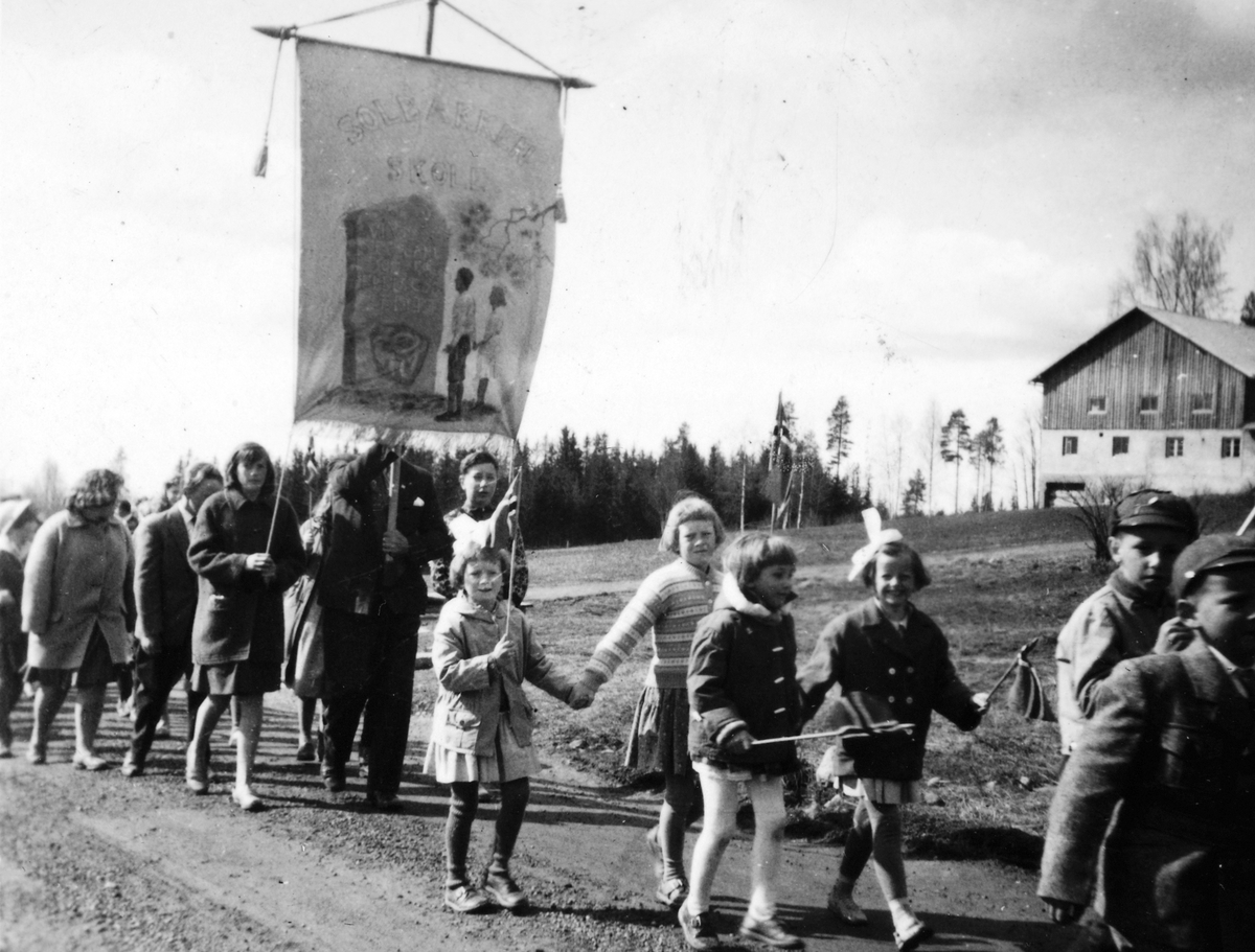 Anno Domkirkeodden, Solbakken skole, Skogbygda i Løten. Skolefane. 1. mai-tog (?)i Skogbygda på 1950-tallet. Engesveen i bakgrunnen.