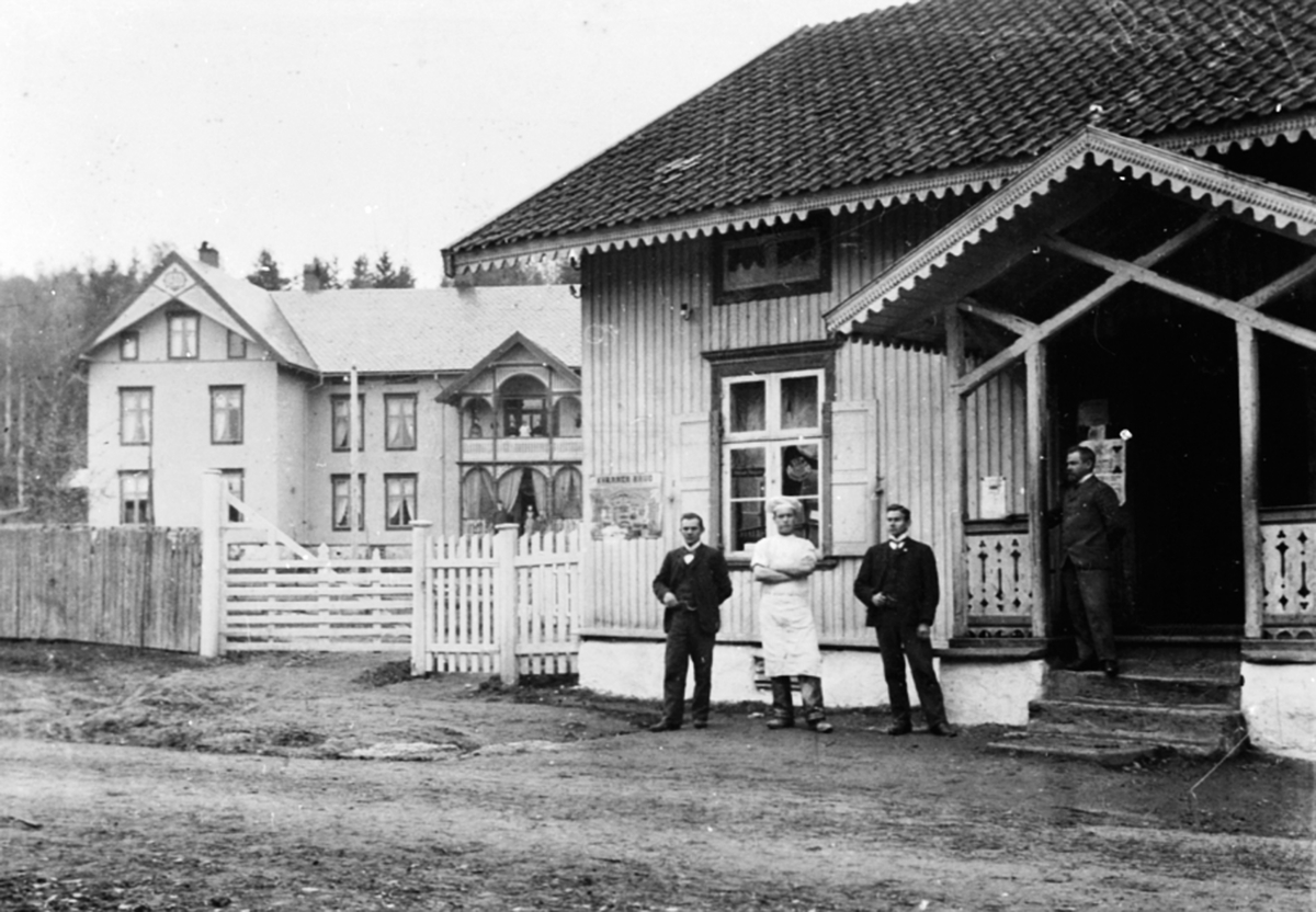 Anno Domkirkeodden, Eksteriør, Ingv. Dehlis landhandleri, Moelv. Fire personer på trappa foran inngangen. Ingv. Dehli, to ekspeditører og en baker.