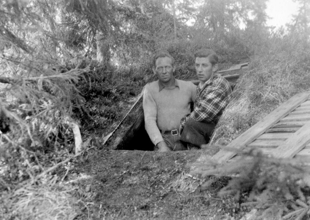 Anno Domkirkeodden, 2 menn fra motstandsbevegelsen, fra venstre er Leif Hov, Bjarne Fredheim. Åpen luke til jordhytte, kamuflert bunkers på Hamarseterhøgda. Bunkersen lå under hytte nummer 19 på Hamarsetra. Milorg, Rauskjørbua.