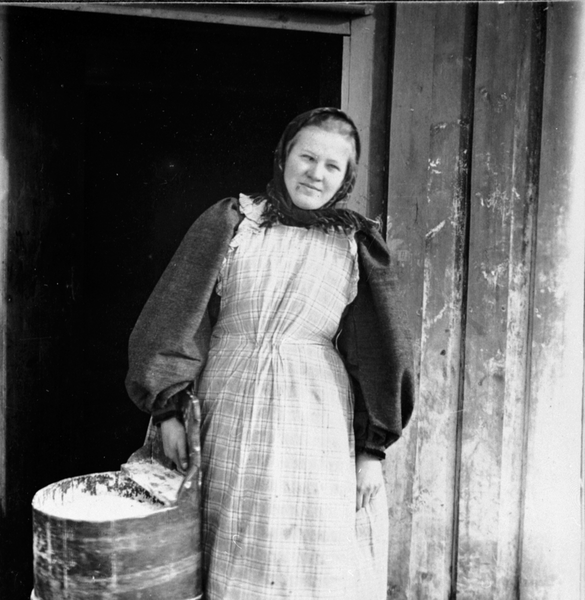 Anno Domkirkeodden, Mimi Løken f.1876 i fjøsdøra på Løken østre, Veldre, Ringsaker. I budeieklær med mjølbutt.
