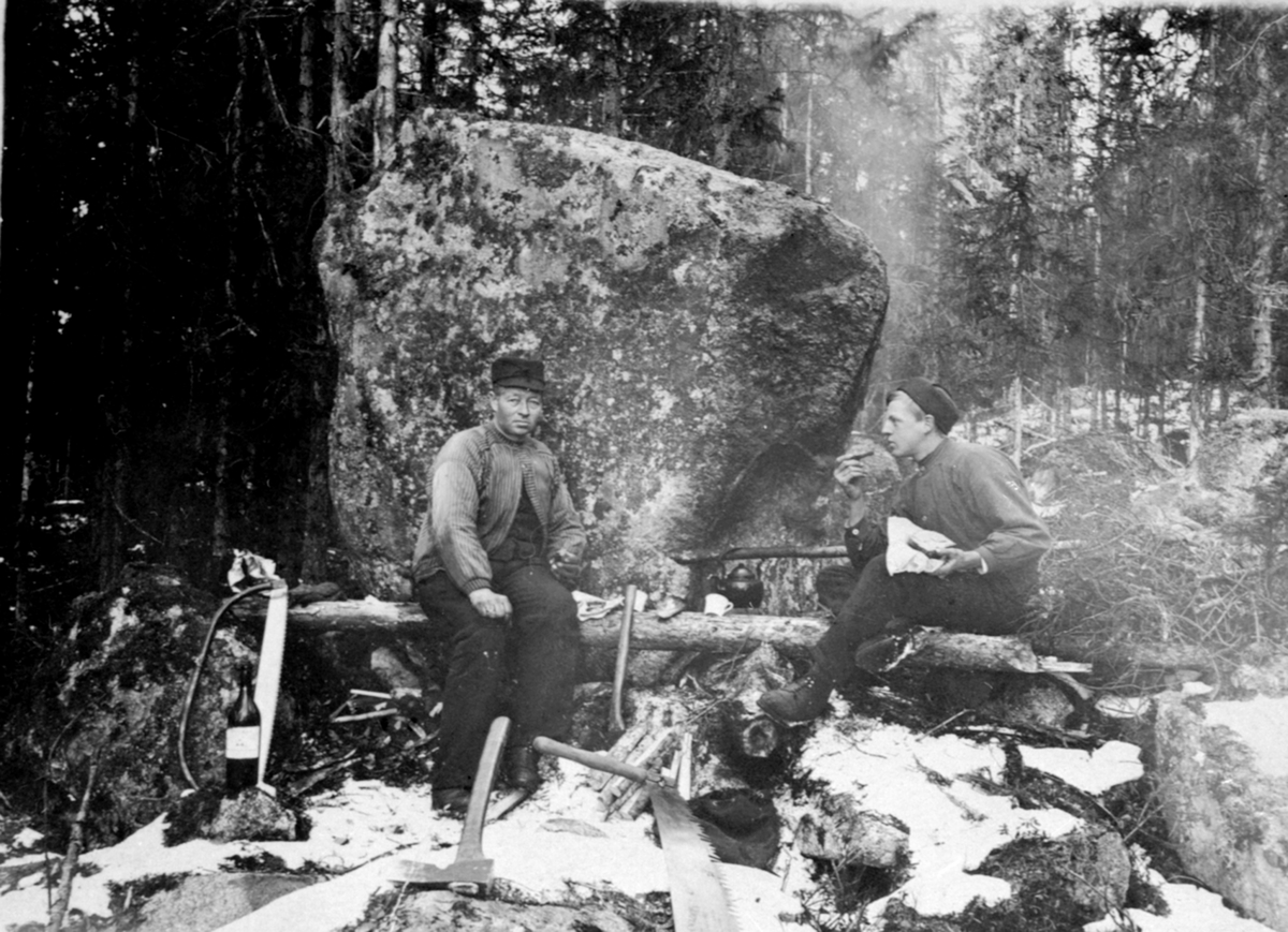 Anno Domkirkeodden, Tømmerhuggere med matpause ved bål. Kaffekjel på sjerding over bålet. Mathias Baardseth og Ole Larsen Jevne. Hogsten foregikk i skogen ovenfor Furuheim, eller Haga Bruk, Næroset, Ringsaker.