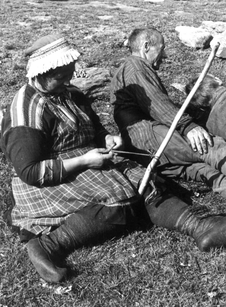 Anna Grostøl, Båndfletting. En kvinne sitter ved siden av en mann og fletter bånd. Lyngen, Troms 1947.