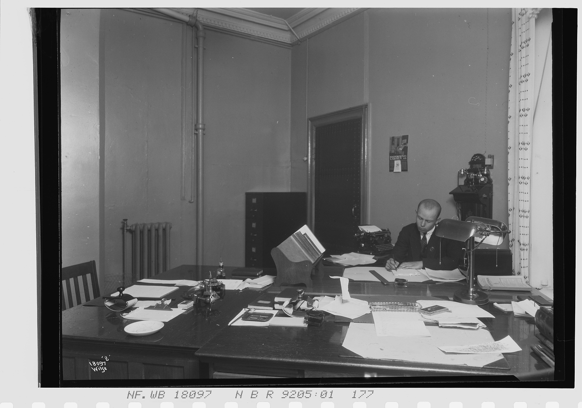 Anders Beer Wilse, Mann sitter ved kontortpult, Vinmomopolet. Fotografert 1924.