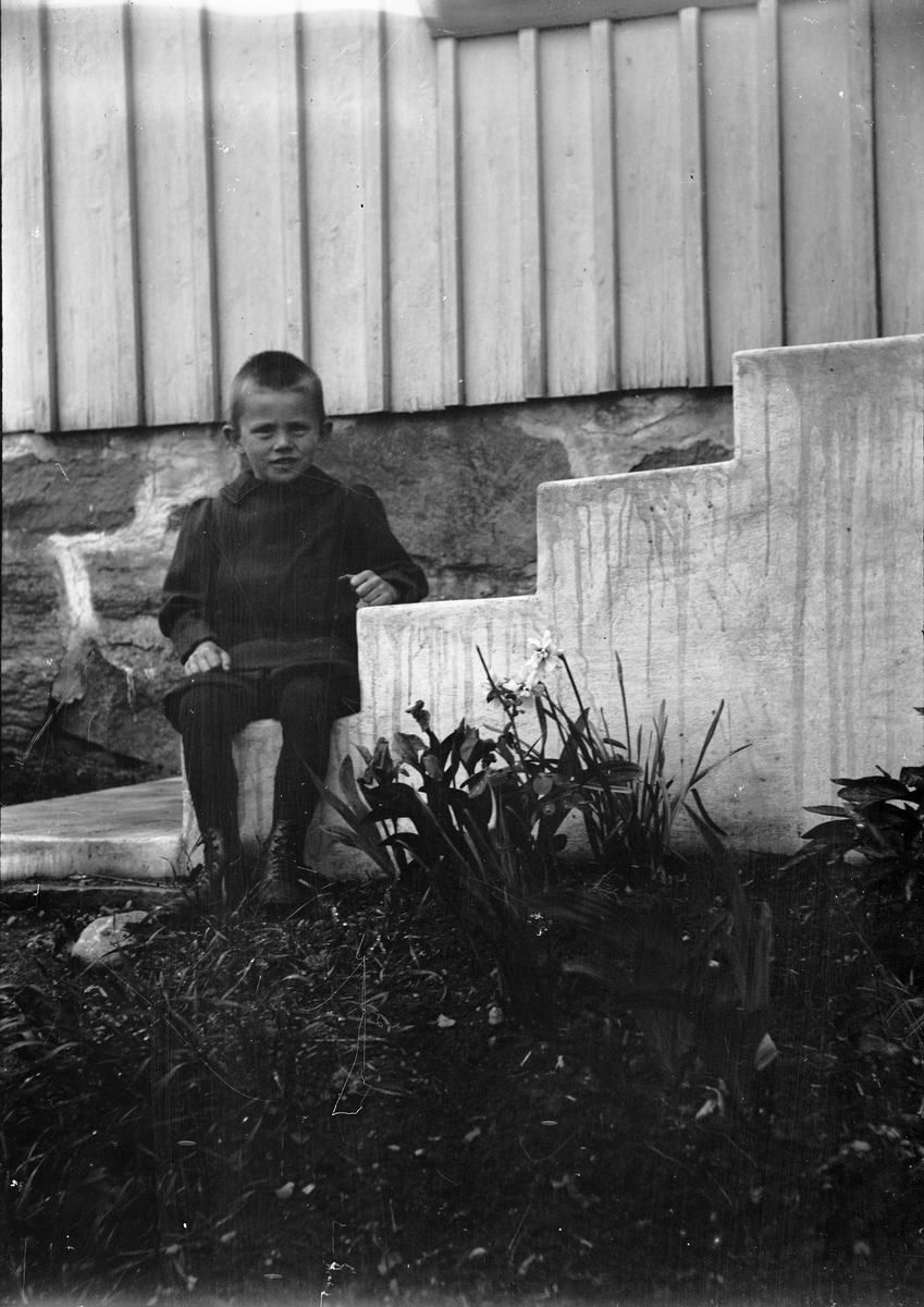 Okänd,, One of Christiane and Ruben Liljefors' sons, probably Alf Liljefors, is sitting out on the stairs, probably in Sweden
