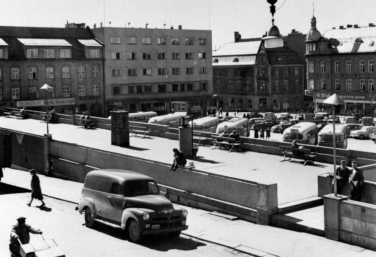 Anno Domkirkeodden, RUTEBILSTASJON, RUTEBILTAKET I HAMAR, GRØNNEGATE MOT ØSTRE TORG, BUSSER OG BILER. FV: MELKEFORSYNINGSGÅRDEN, HOTEL ASTORIA, GODAGERGÅRDEN OG GRANERUDGÅRDEN, I FORGRUNNEN EN VAREBIL: CHEVROLET PANEL DELIVERY 1954.