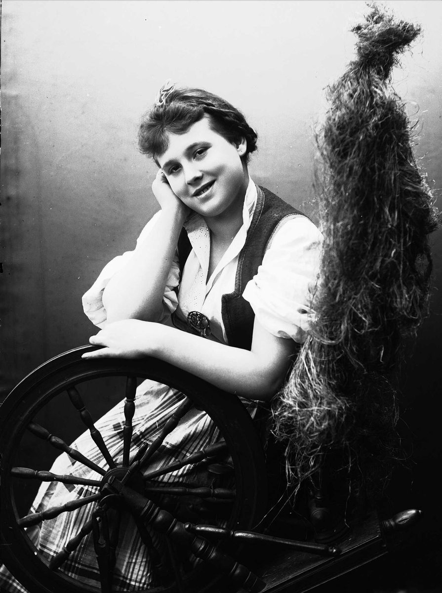 Solveig Lund, Studioportrett av kvinne i drakt, som sitter ved en rokk. Bakgrunnen er nøytral.