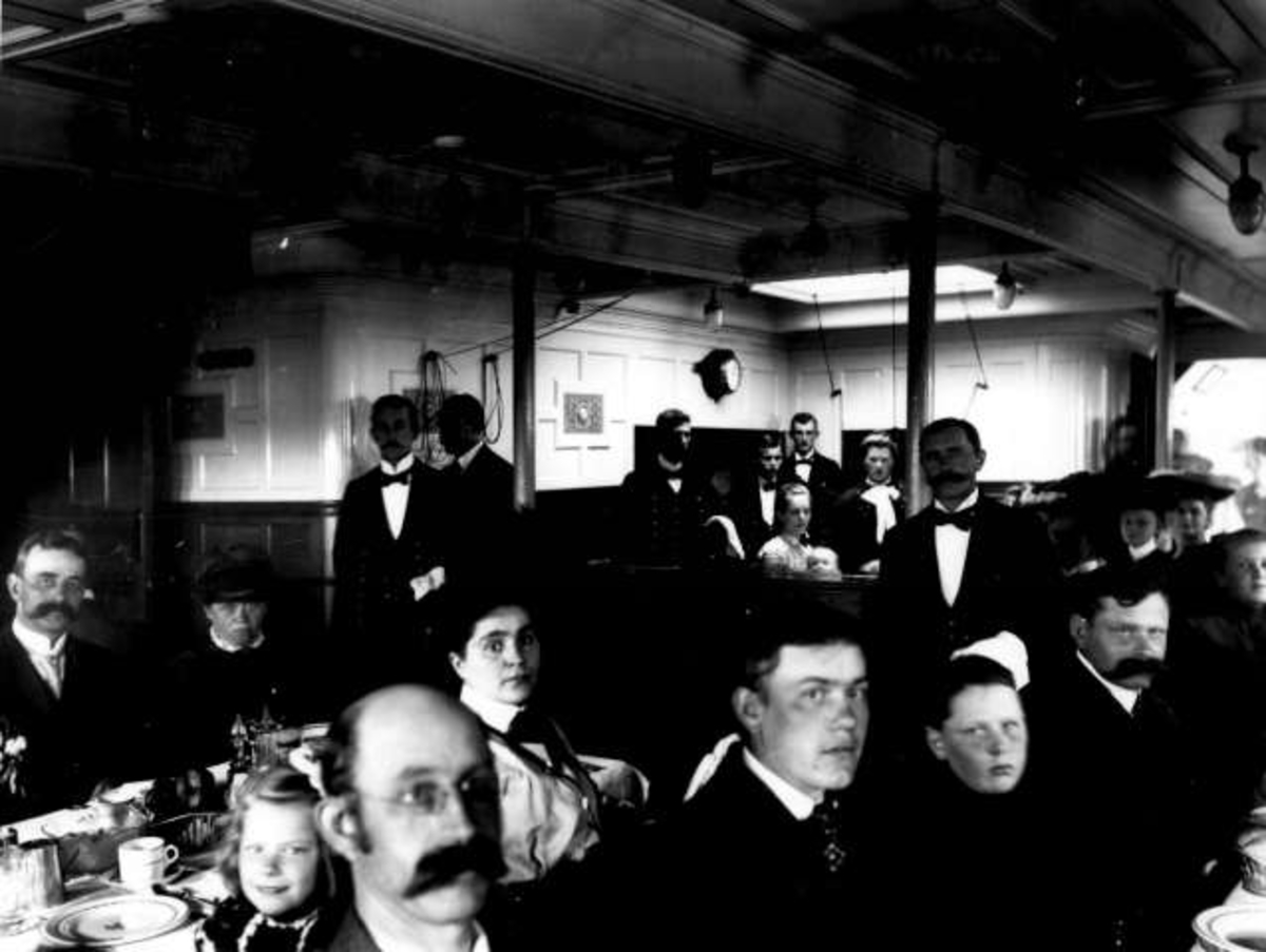 Anders Beer Wilse, Utvandrere sitter i matsalen ombord i skipet S.S. Hellig Olav i 1904.