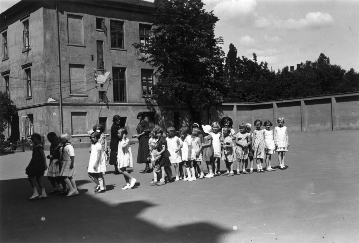 Hermann Christian Neupert, Oslo. 1932. Siste skoledag i skolegården. Småpiker. Lærerinner.