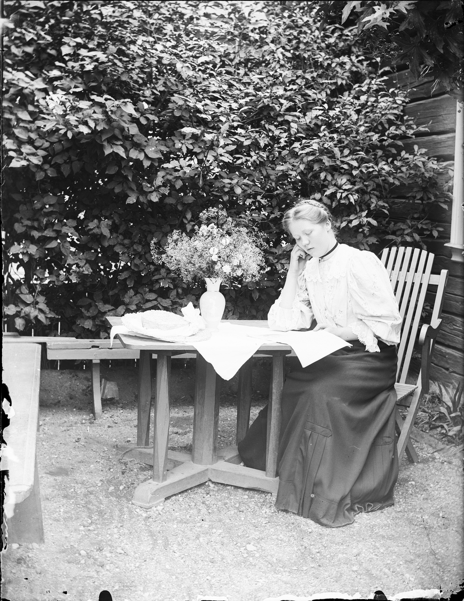 Skötsner-Edhlund, Ruth Skötsner sitter ute vid bordet och läser, Östhammar Uppland