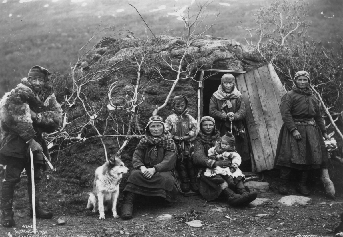 Axel Lindahl, Svenske samer og en hund utenfor døråpningen til en gamme, fem voksne og to barn. Nord-Norge 1906.