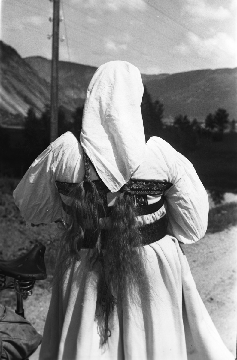 Anders Beer Wilse, Kvinne i setesdalsdrakt har gått av sykkelen for å beundre utsikten foran seg.