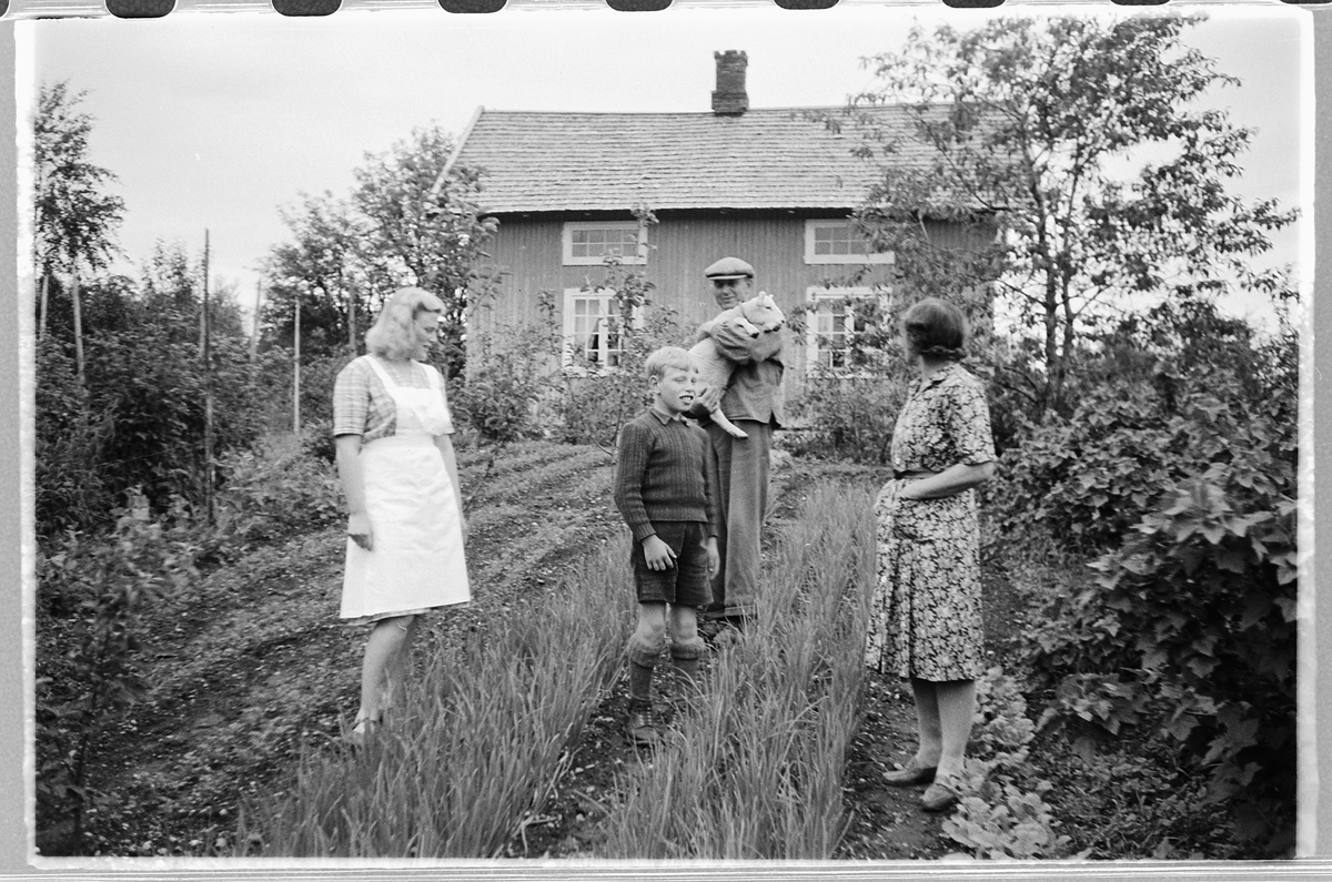 Håkon Prestkværn, To kvinner, en mann og en gutt i en hage.