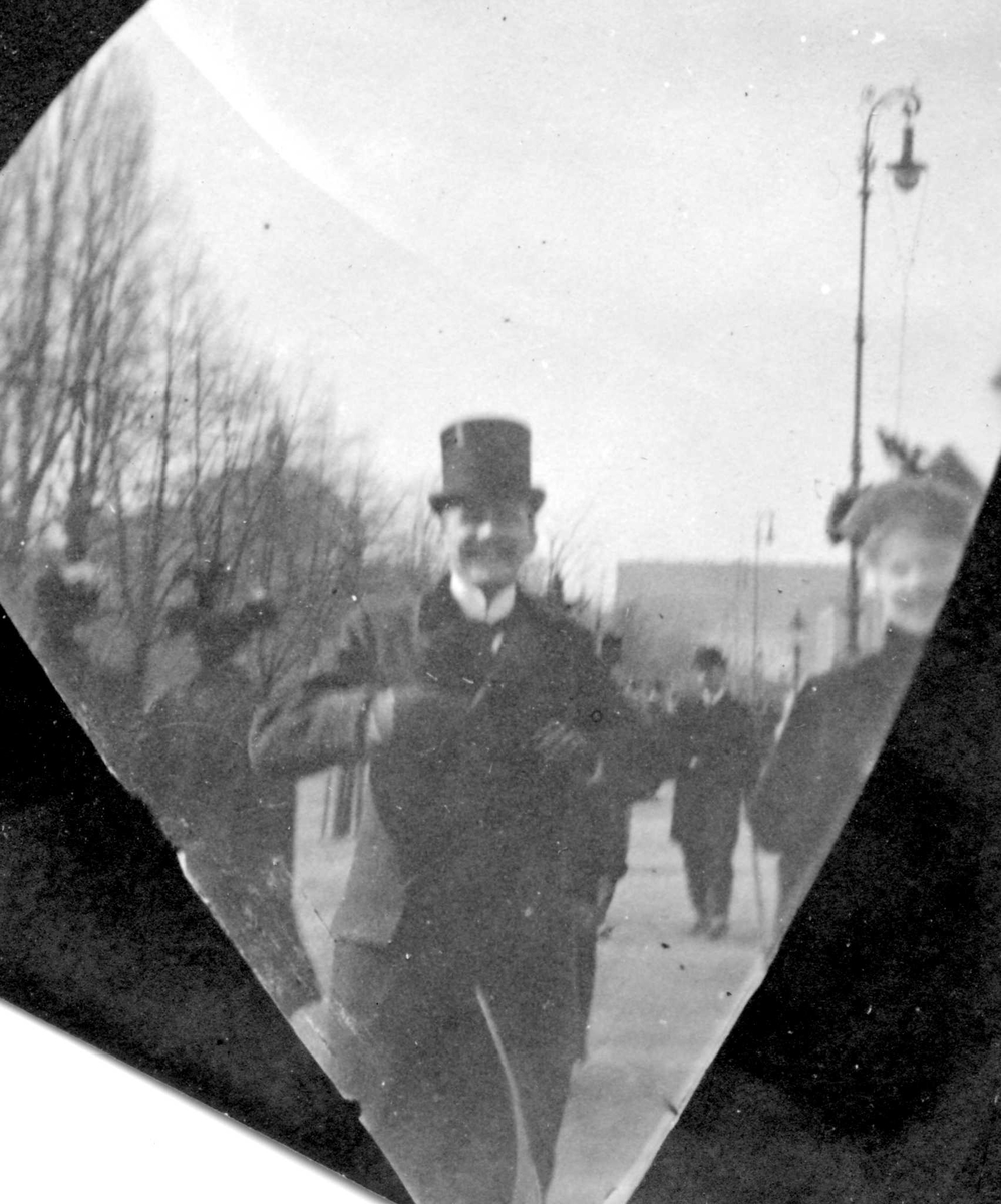 Fredrik Carl Mülertz Størmer, Dr. Petter Anker og frk. Marie Reimers spaserer på Karl Johans gate, Oslo, med Slottet bak.