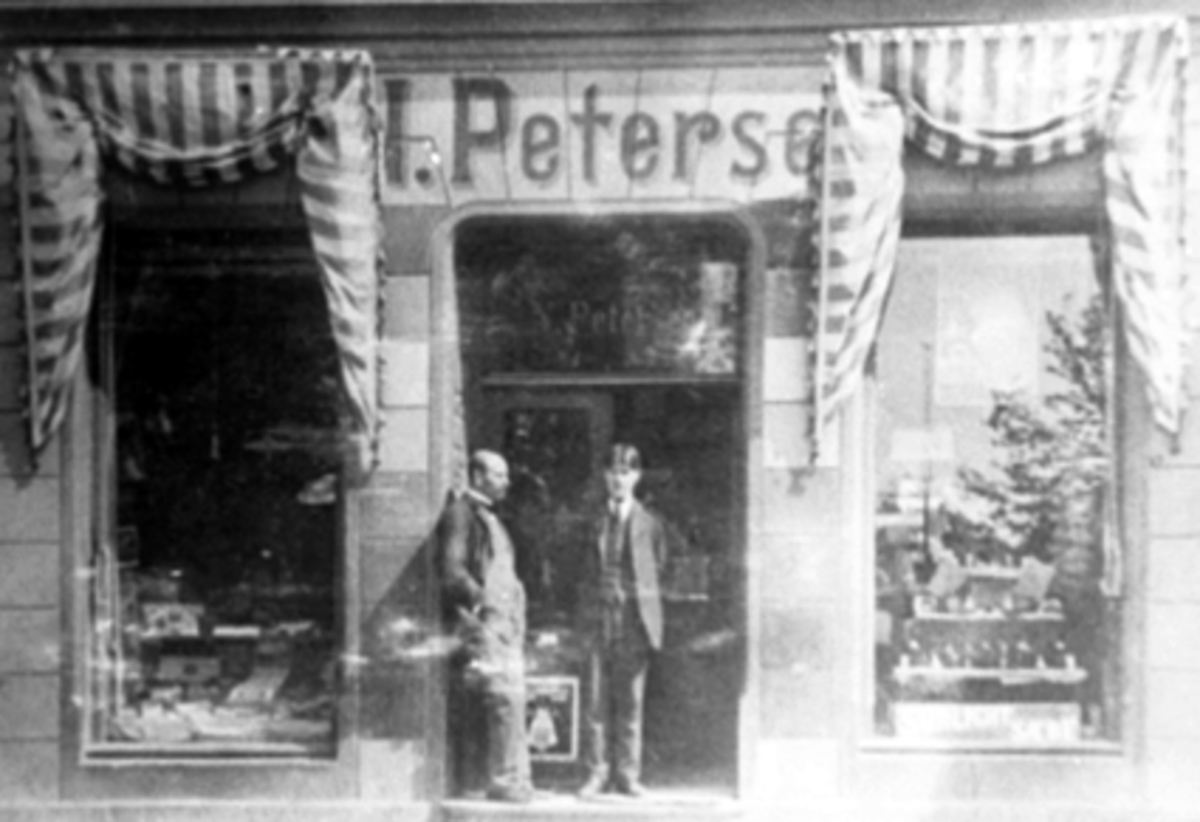 Anno Domkirkeodden, F. Petersens Fargehandel, Strandgata, Hamar. T.v. Filip Petersen, ukjent ekspeditør. Eksteriør, markiser.