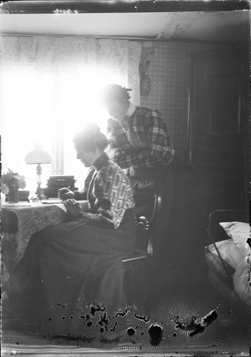 Skötsner-Edhlund, Woman stands by Ruth Skötsner who sits at the table and writes, Östhammar Uppland