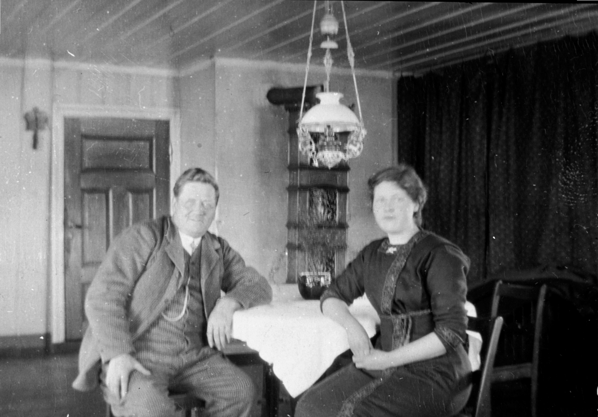 Anno Domkirkeodden, Interiør, stue, bord, parafinlampe, etasjeovn. Ole og Lovise Nerlien, Lien nedre, Nes, Hedmark.
