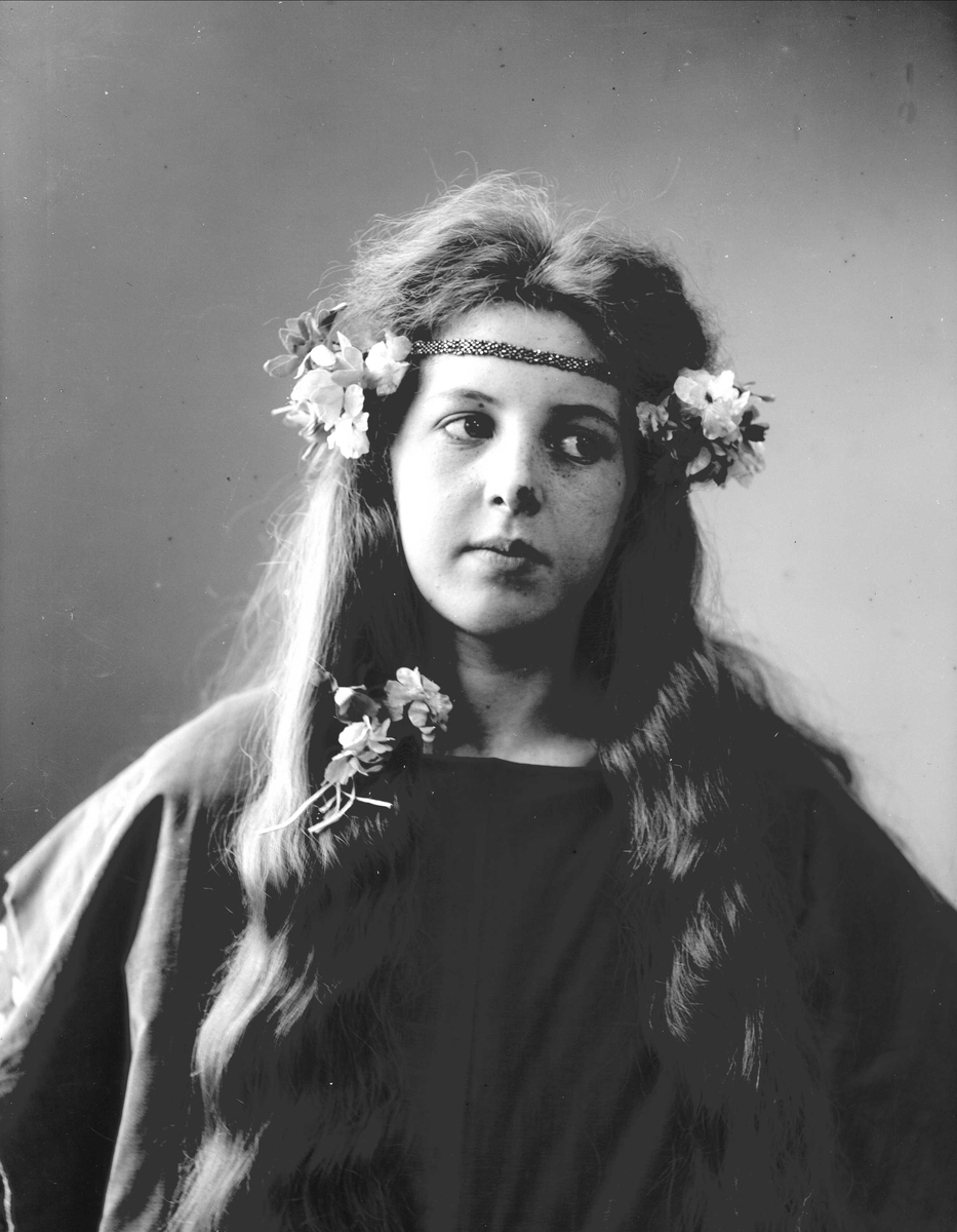 Solveig Lund, Studioportrett av kvinne i kostyme med mørk overdel og blomster i håret.