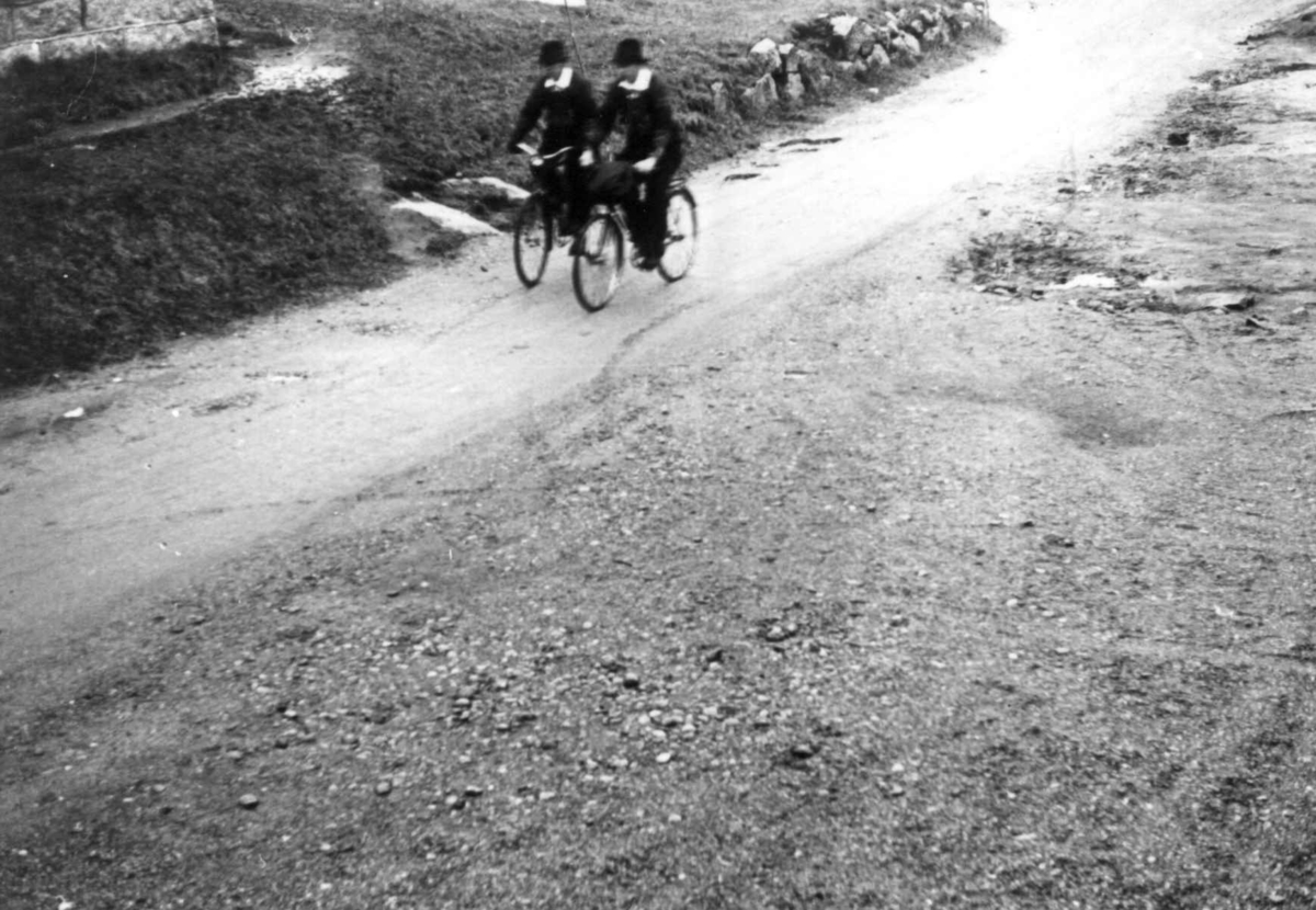 Anna Grostøl, Valle, Aust-Agder 1938. Bededag. To menn på sykler på vei til kirken.