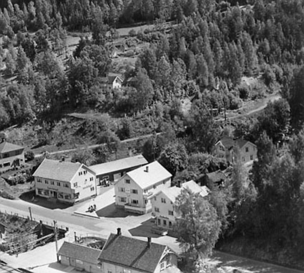 Widerøes Flyveselskap A/S, Flyfoto, Espa, Stange. F. v Holtet, Solli (samvirkelaget) med bakeriet bakenfor, Brodal, Nordheim, Espa Jernbanestasjon. Opp i skråningen bak Nordheim ligger Bækkedal. Posten har holdt til i Holtet fra 1964-1981, Brodal fra 1981-1993 og Espa stasjon fra 1881-1963. Flere opplysninger se boka "Handel…