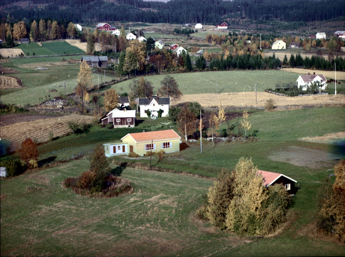 Widerøes Flyveselskap A/S, FLYFOTO HARASET. VALLSET. NORDSET 378-18, SVEEN 380-9, Huset bakløvtrærne er ei hytte på Haraset leirsted, eid av Indremisjonen. Det gule huset er et slags forsamlingshus. Til høyre med flaggstang ser vi hovedhuset på Sveen. Midt på bildet ser vi fem like hus. Området ble lokalt bare kalt Feltet. Ø…