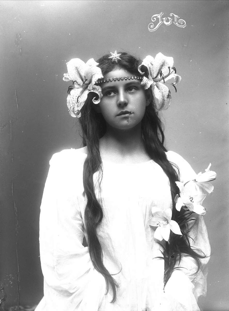 Solveig Lund, Studioportrett av kvinne i drakt med smykker og blomster i håret.