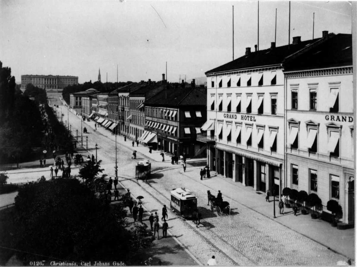 Axel Lindahl, Karl Johans gate, Oslo 1885-90. Gatebilde med Grand Hotel, Eidsvolls plass, mennesker og hestetrikk. Sett mot Slottet.