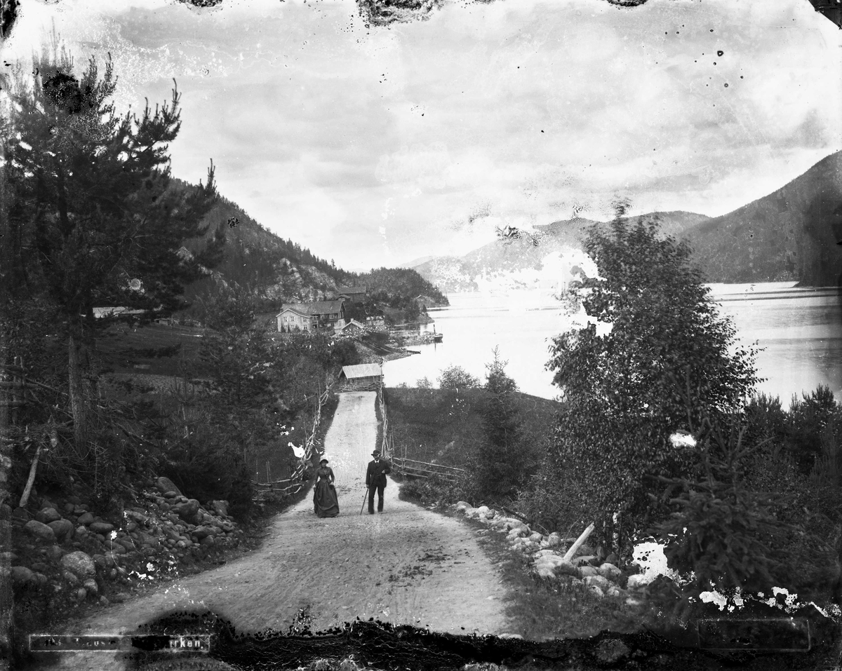 Marthinius Skøien, Tinnoset, Gransherad, Notodden, Telemark. Par gående på vei ved innsjø.