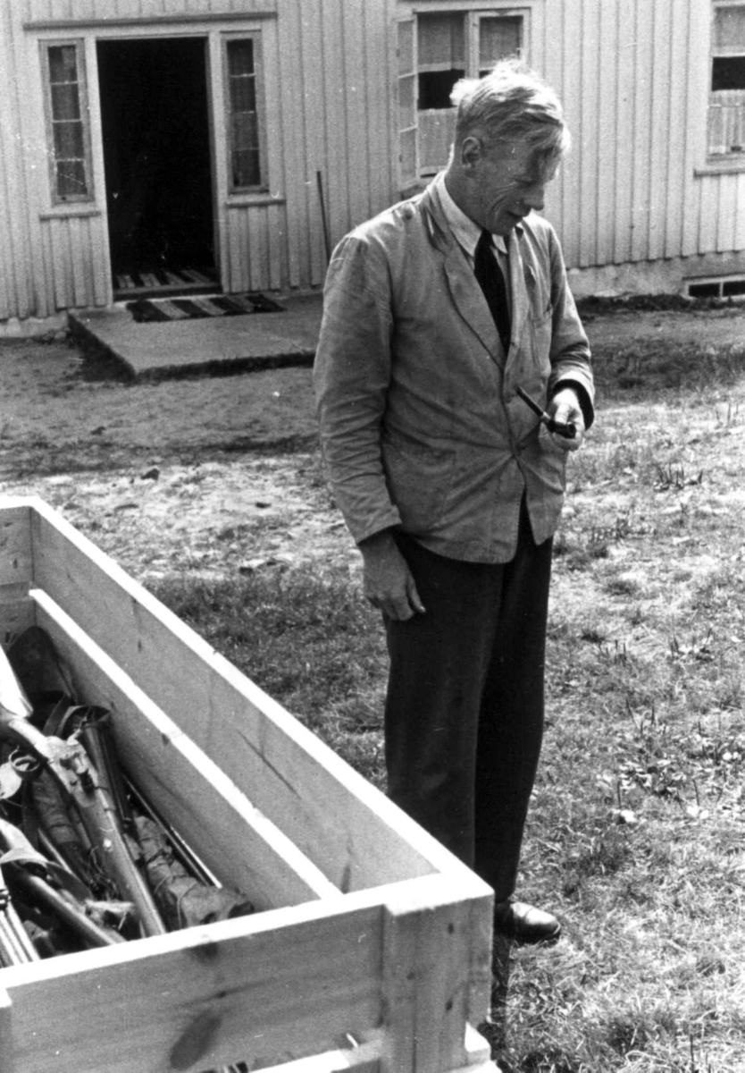 Anna Grostøl, Knut Vatnestrøm står foran et hus ved en kasse med geværer. Frostemyr 1941.