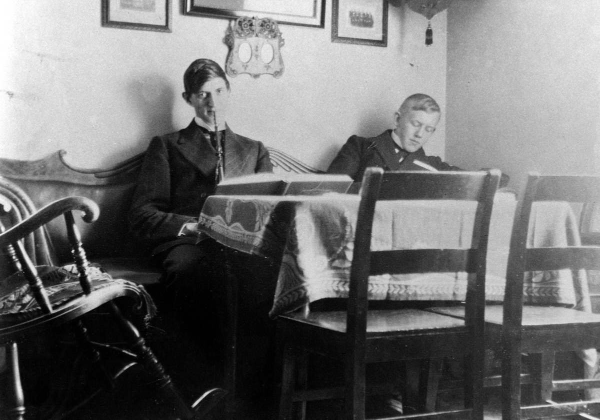 Anno Domkirkeodden, INTERIØR: STUE MED GYNGESTOL, BORD, STOLER, FOTOGRAFIER, HYLLE, GRUPPE: 2 UNGE MENN: TRYGVE FREMSTAD MED LANGPIPE, EIVIND AALSTAD, ÅLSTAD GÅRD