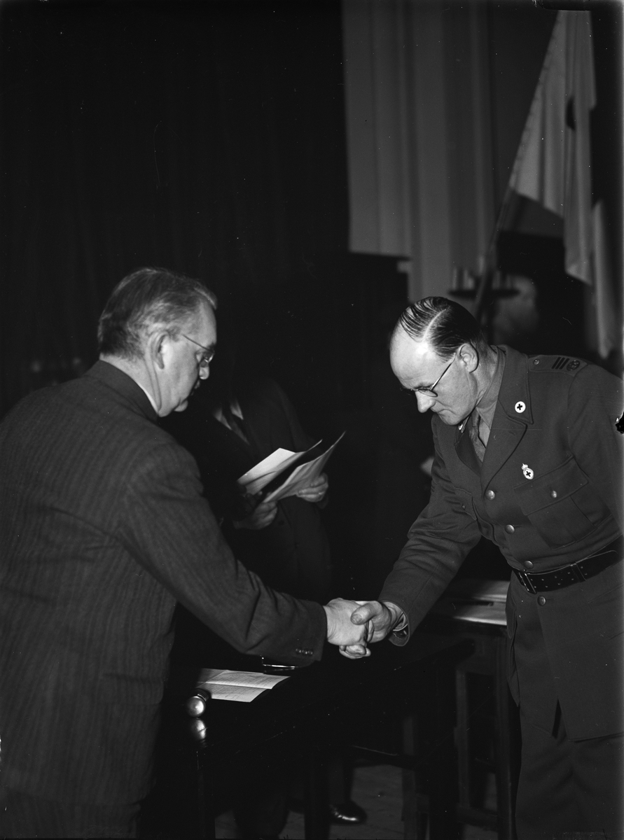 Paul Sandberg, Landshövding Hilding Kjellman shakes hands with a uniform dressed man with marks from the Red Cross, Uppsala in February 1944