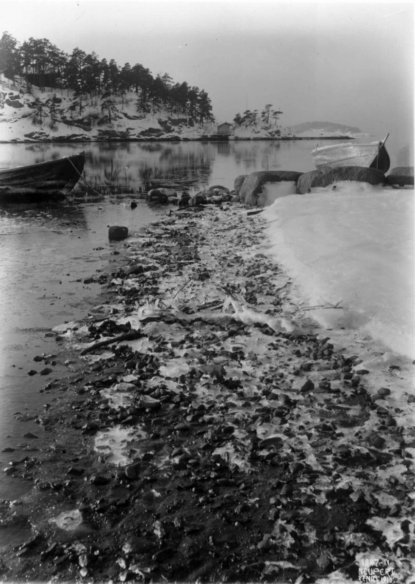 Hermann Christian Neupert, Oslo, Ormøya 1910. Strandparti. Vinter med is og baugen av en båt.